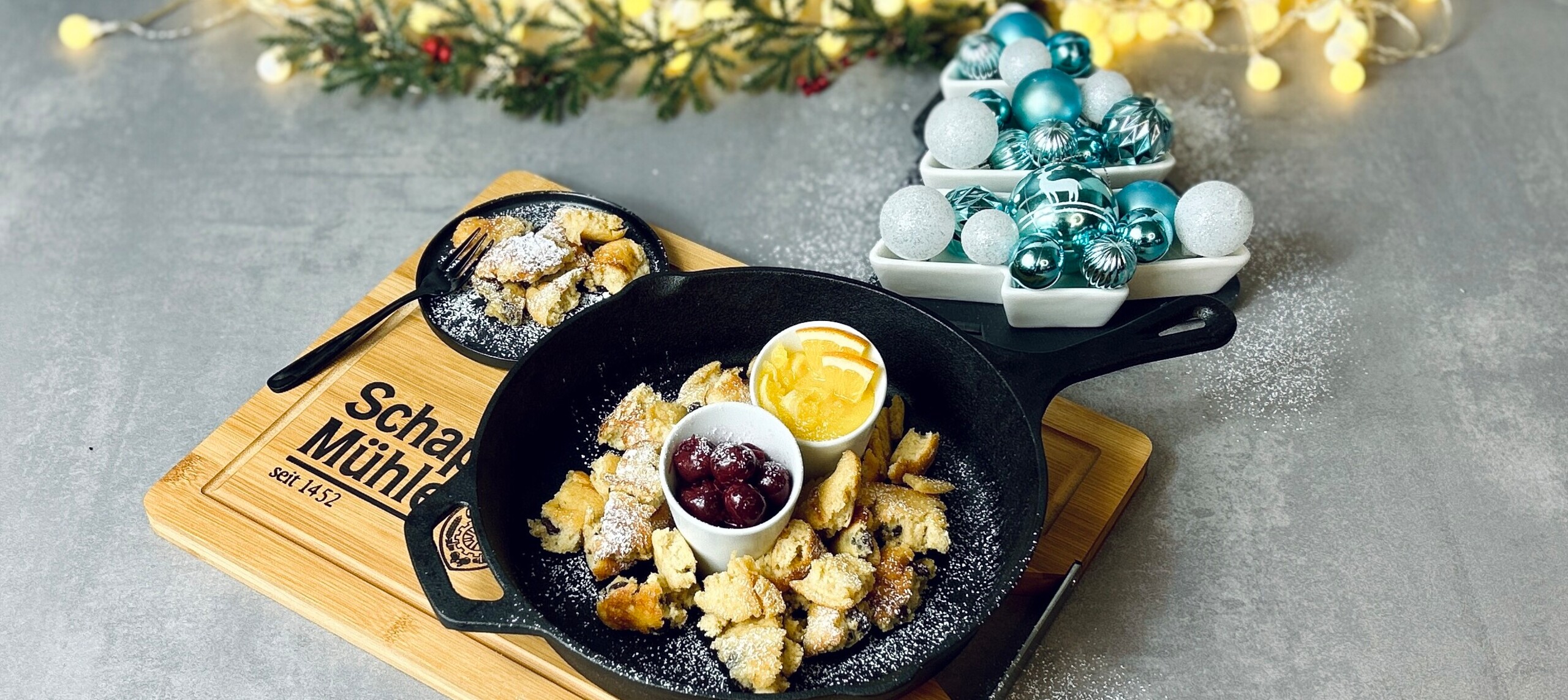 picture of the kaiserschmarrn in a pan with cherrys and orange slices in little bowls